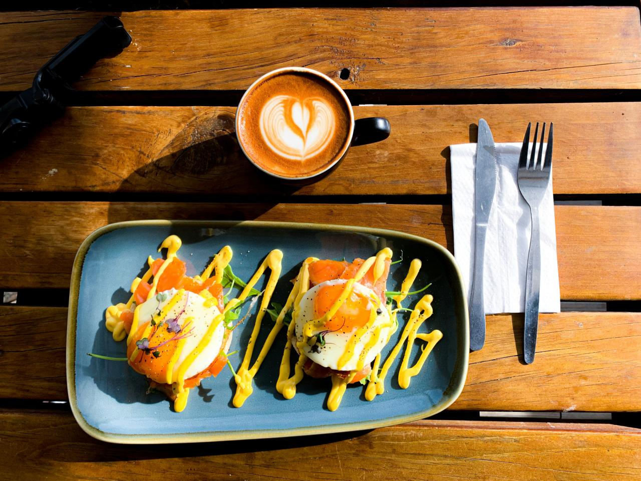 stainless steel fork on black ceramic plate beside brown ceramic mug